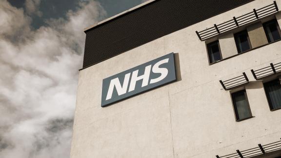 Sepia-toned image of the NHS logo on a hospital building