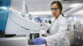 A healthcare scientist in a laboratory, using a machine.