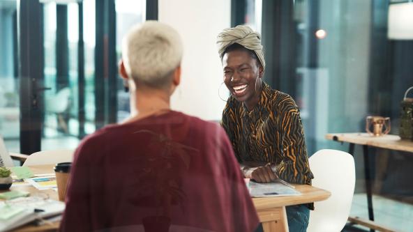 Two colleagues laughing during a meeting.