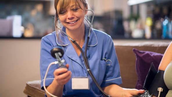 A midwife with a patient on a home visit, checking her blood pressure.