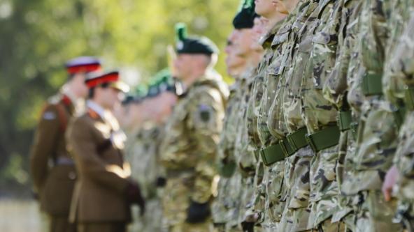 Armed forces personnel in camouflage uniform standing in formation during a formal inspection