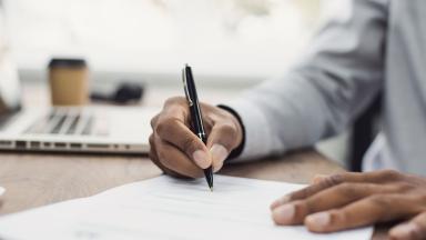 Someone signing a form with a pen.
