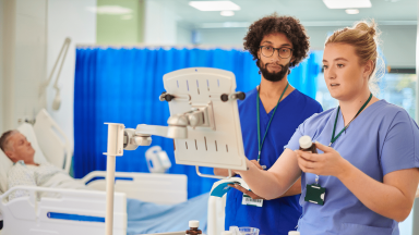 Two nurses reviewing medical equipment in a hospital setting