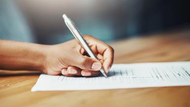 A hand ticking a survey with a pen.