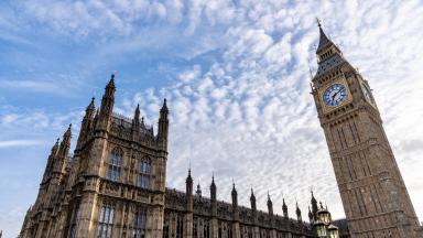 View of the Palace of Westminster and the Elizabeth Tower, commonly known as Big Ben, under a partly cloudy sky.