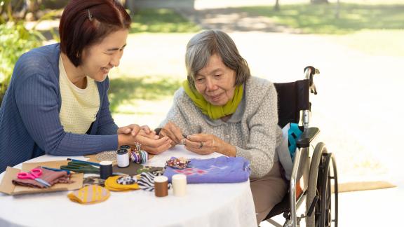 A patient and carer, crafting at an outside table.