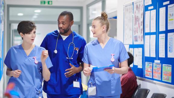 A diverse group of healthcare staff walking along a hospital corridor.