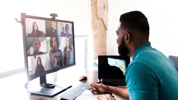 A homeworker taking notes while in a video call.