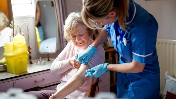 A nurse on a home visit, giving an injection.