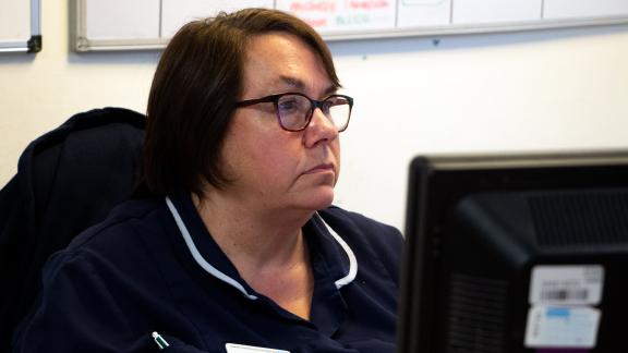A senior nurse at a computer.