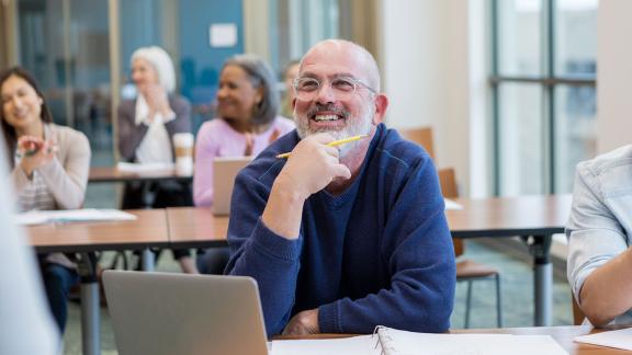 A smiling, thinking man, taking part in a webinar.
