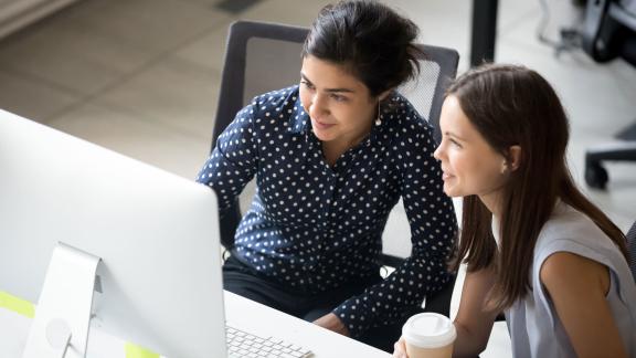 Two colleagues in discussion at a computer.
