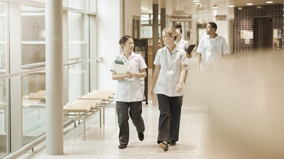 A sepia-toned image of a diverse group of nurses walking down a corridor