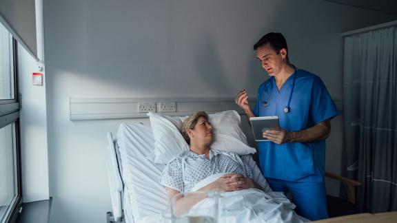 A doctor speaking to a patient in a hospital bed