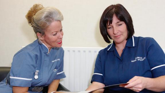 Two nurses talk while reading
