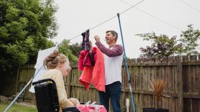 A carer putting the washing out and laughing with his daughter.