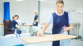 A hospital cleaner, cleaning a tray.