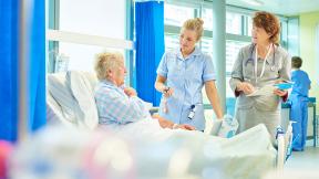 A doctor and nurse at a patient's bedside.