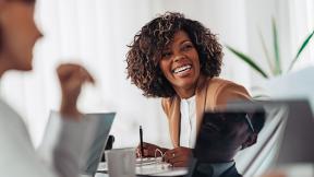 An office worker laughing during a meeting.