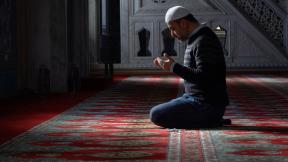 A man kneeling and praying in a mosque. 