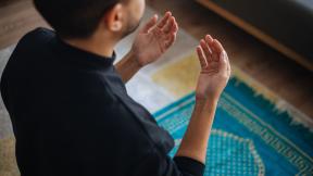 A man kneeling on a prayer rug and praying.
