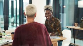 Two colleagues laughing during a meeting.