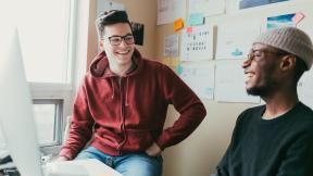 Students in a dorm room, laughing.