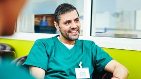 A smiling surgeon sitting in a chair.