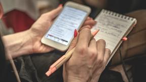 A delegate making notes on a phone and notepad. 