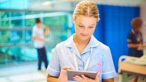 A nurse checking a tablet computer.