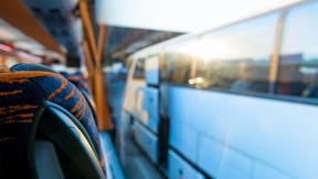 A an empty coach seat with a view of another coach through the window.