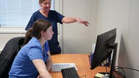 Health T Level student at a computer taking direction from a supervisor