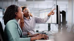 Young woman learning from mentor at a computer