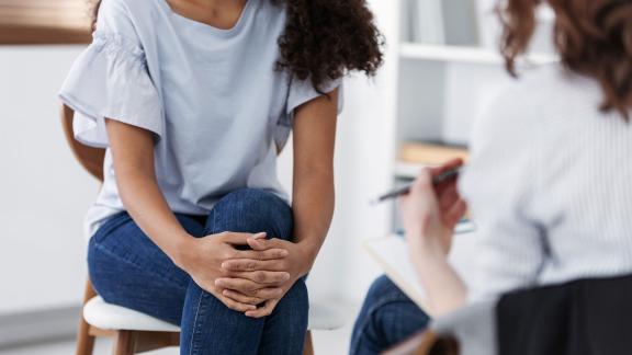 A patient in counselling, holding their knee.