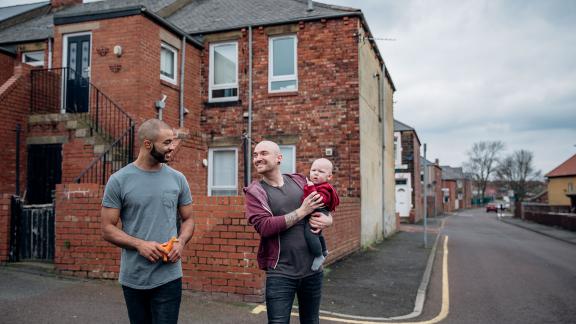 A couple holding their baby outside a house.