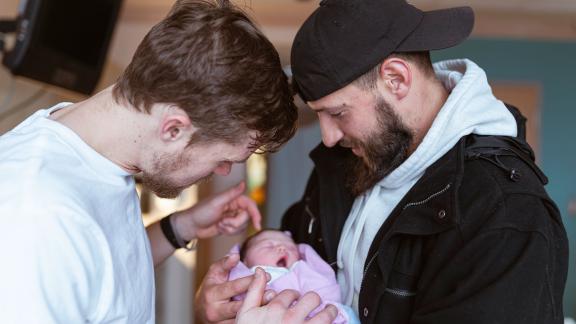 A couple cradling their newborn baby in hospital.