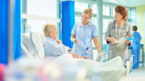 A doctor and nurse at a patient's bedside.