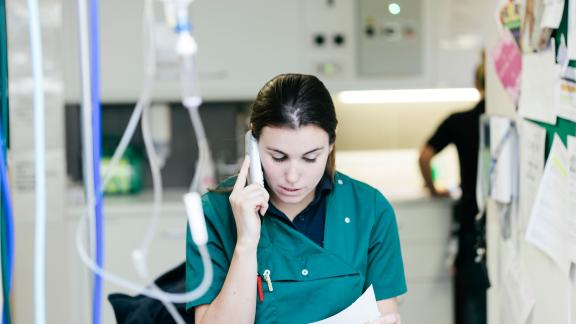 A doctor on a hospital ward, making a phone call. 