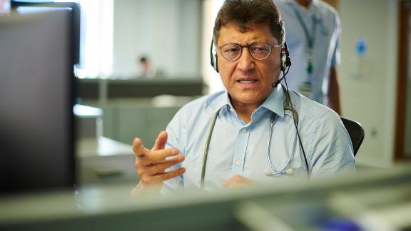 A doctor at a computer, using a headset.