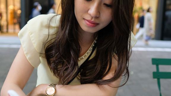 A young woman at an outside table, filling in a form.