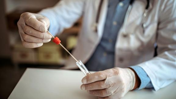 A healthcare scientist holding a swap and test tube.