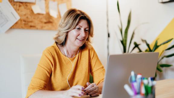 A home worker wearing earphones, on a video call.