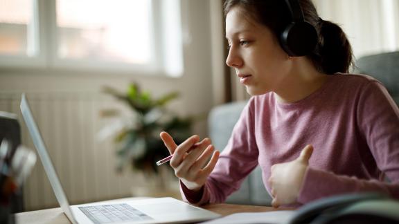 A home worker on a video call, wearing headphones.