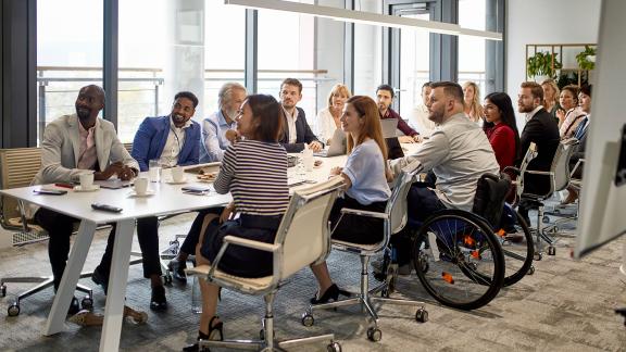 A diverse office meeting around a very long table.