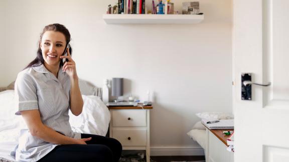 A medical student in their bedroom, talking on the phone.