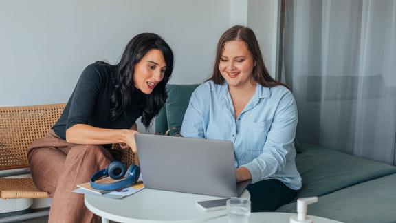 Two home workers in discussion by a laptop.