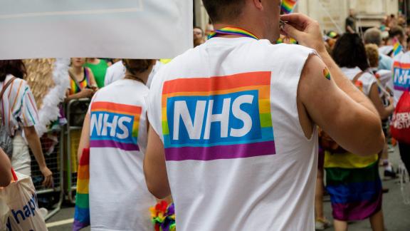 An NHS pride logo on the back of a t-shirt at a march.