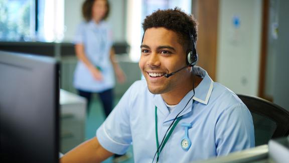 A nurse in a headset, using a computer.