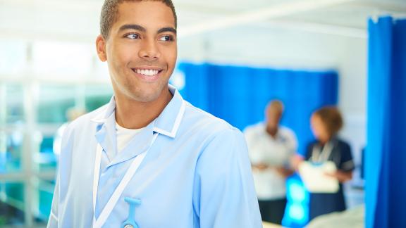 A nurse on a ward, smiling. 