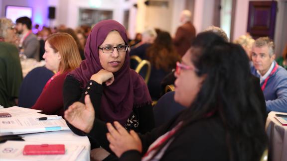 A women in hijab listening at a conference